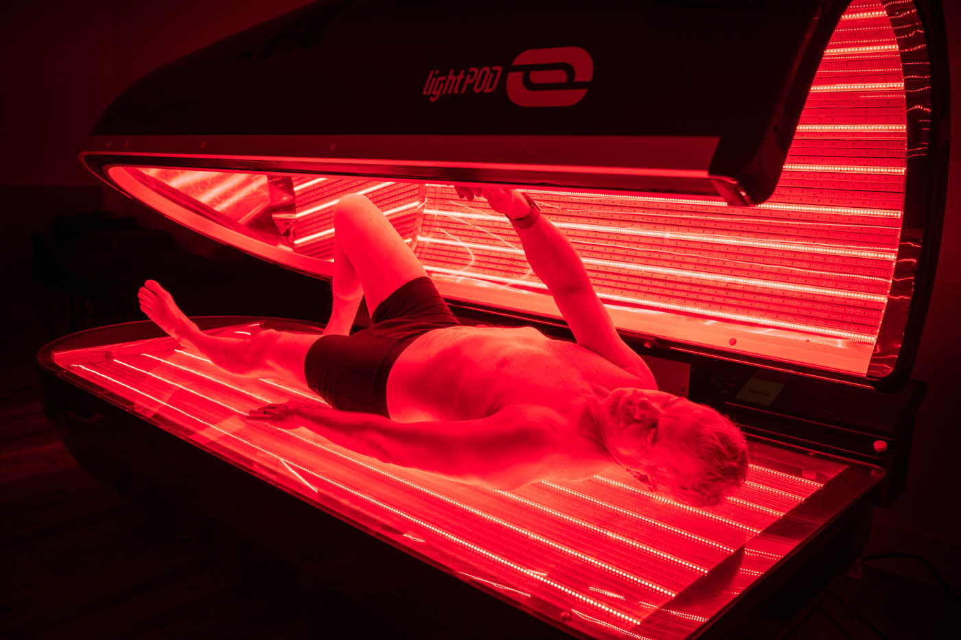 A man getting into a dark pod with bright red light, contact Light Lounge today for your infrared light therapy in St. Charles.