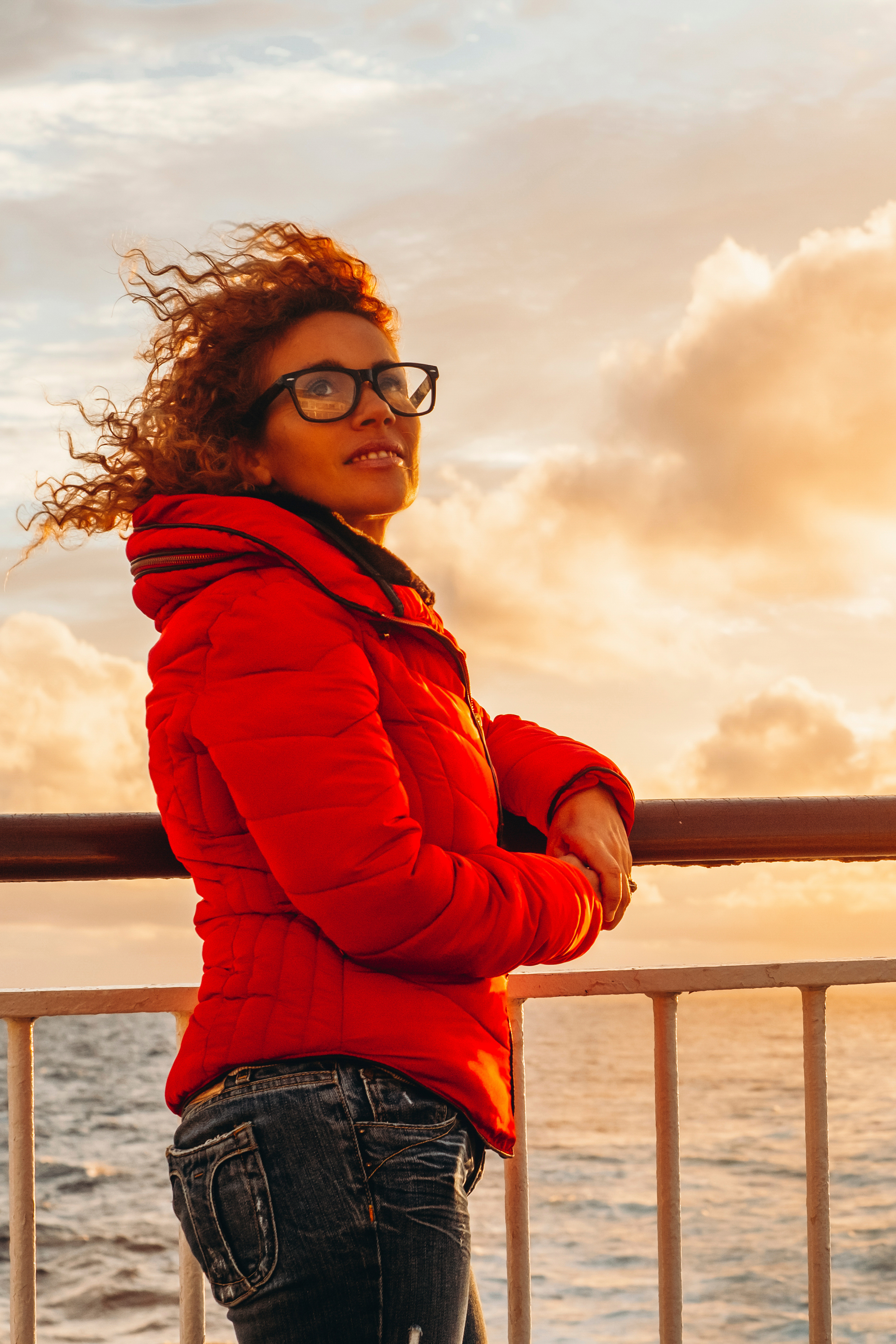 A woman in a red jacket standing by the ocean - learn how Light Lounge can help you with back pain management in Holland, MI.