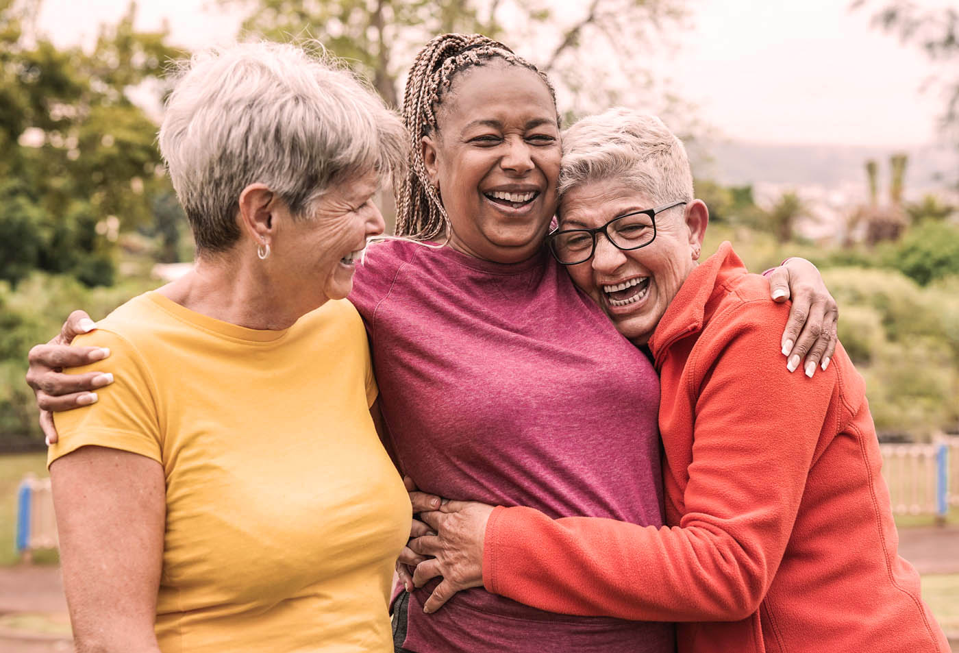 A group of elderly women laughing and hugging each other - discover Evergreen multiple sclerosis pain treatment today.