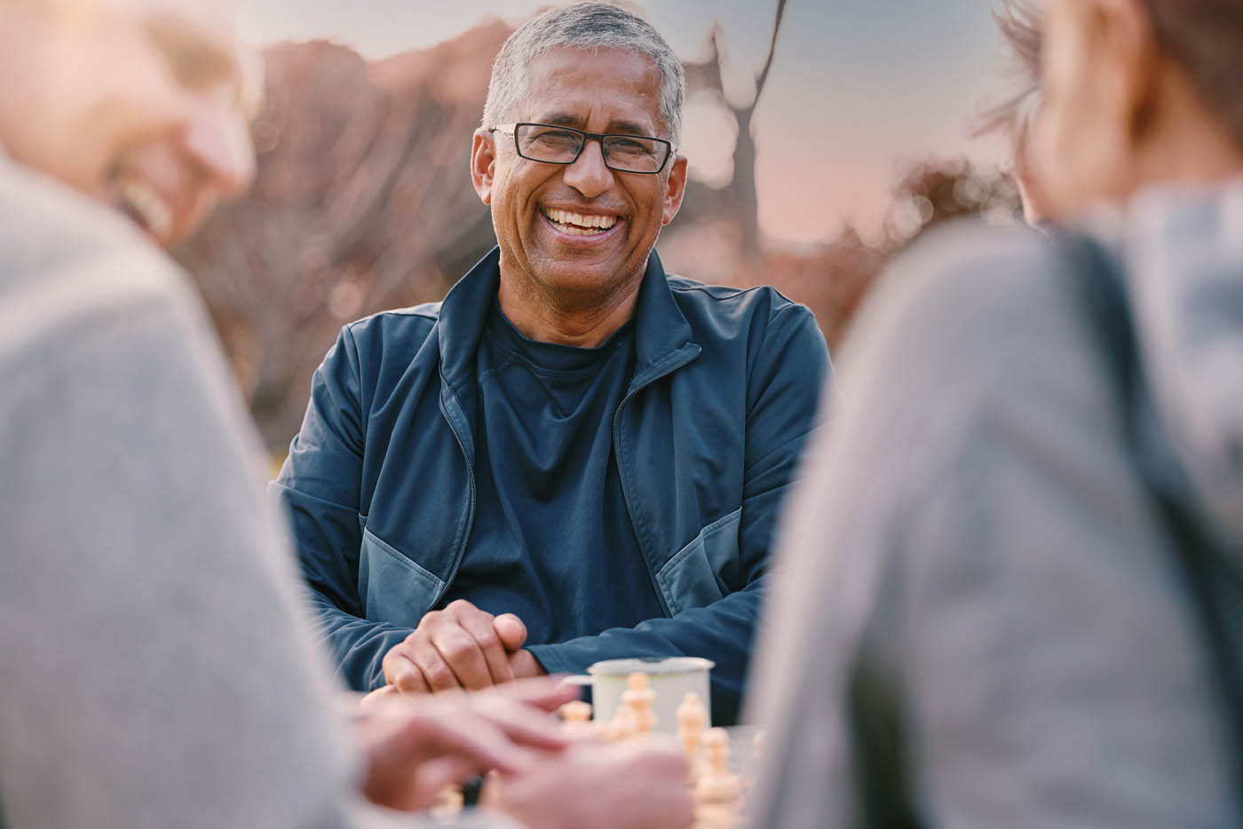 An elderly man laughing at a table with his friends, enjoying the benefits of Light Lounge Scottsdale.