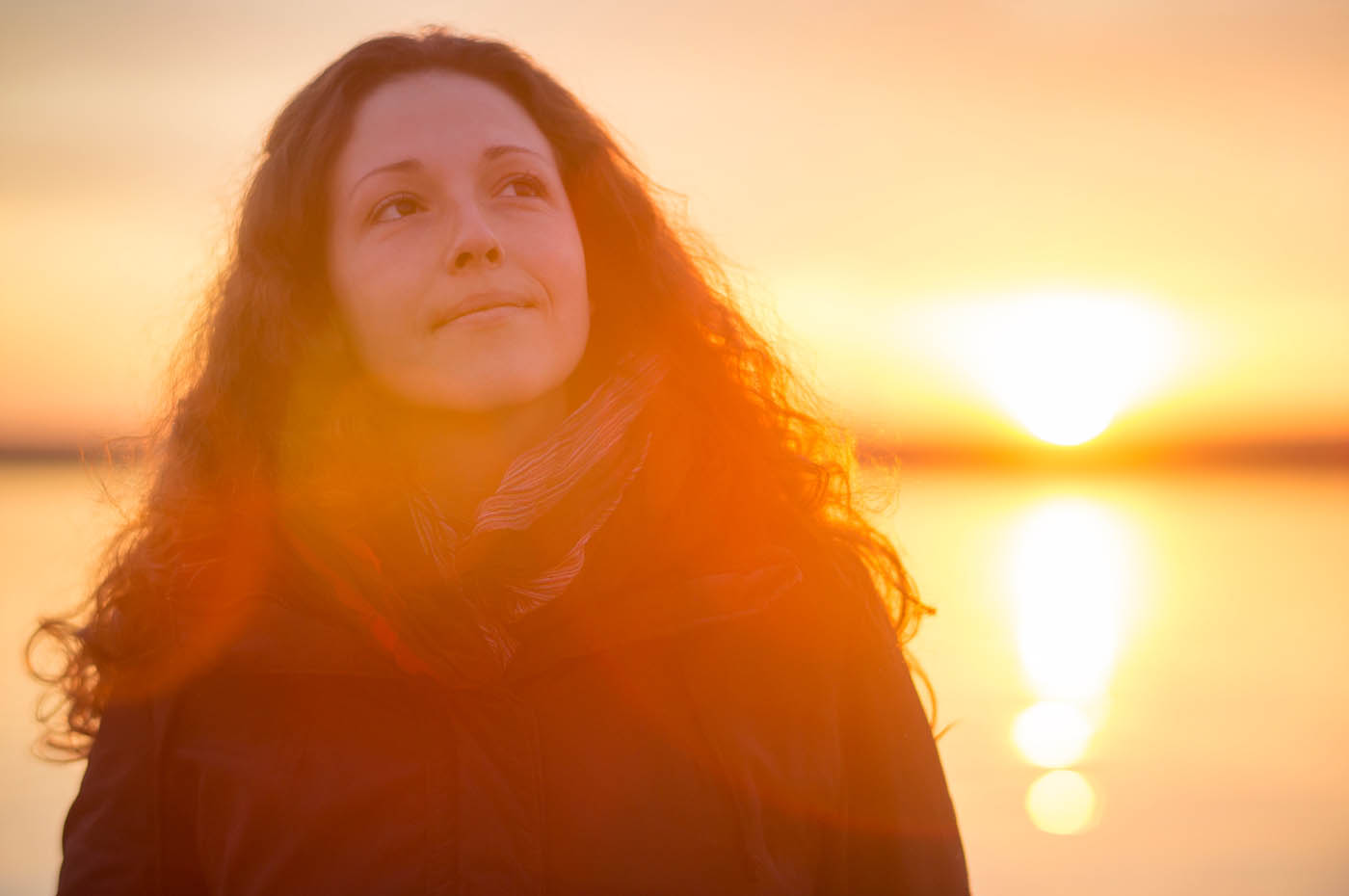 A women standing in front of a red light sunset, learn the benefits of phototherapy in St. Charles, MO.