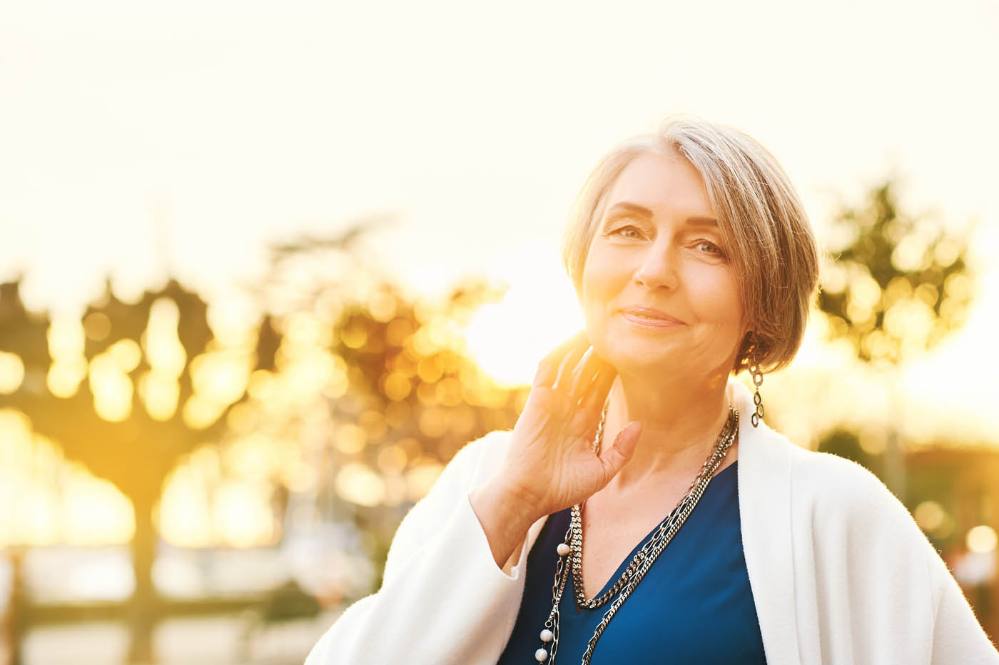 An woman with radiating skin in her late 40s standing in front of a sunset, learn the benefits of getting a photofacial in Arvada, CO.