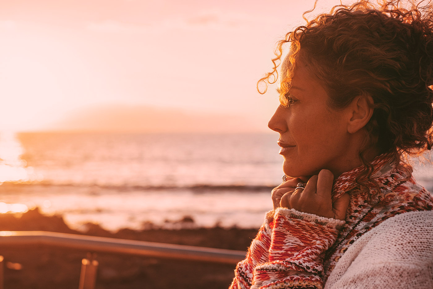 An women with radiating skin in her late 40s standing in front of a sunset, learn the benefits of our photofacial in St. Charles.
