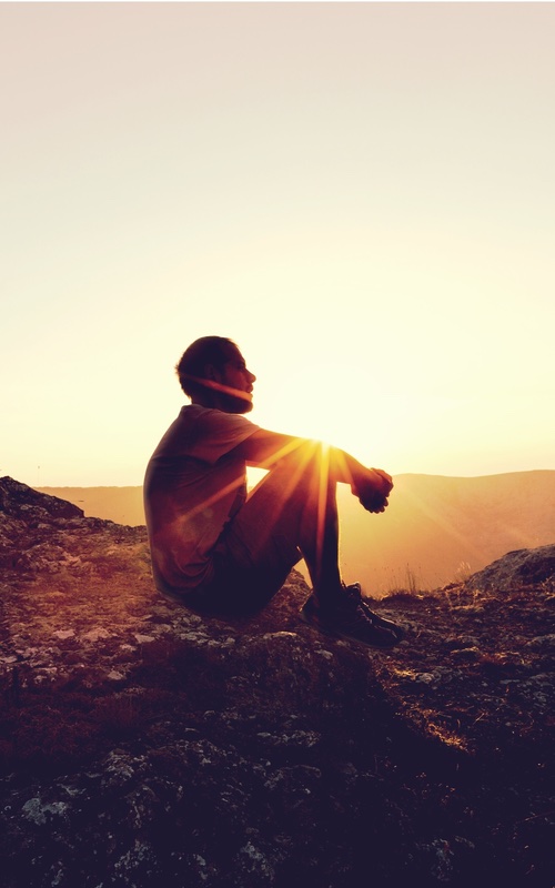 A person improving themselves without supplements as they sit and look out at the rising sun.