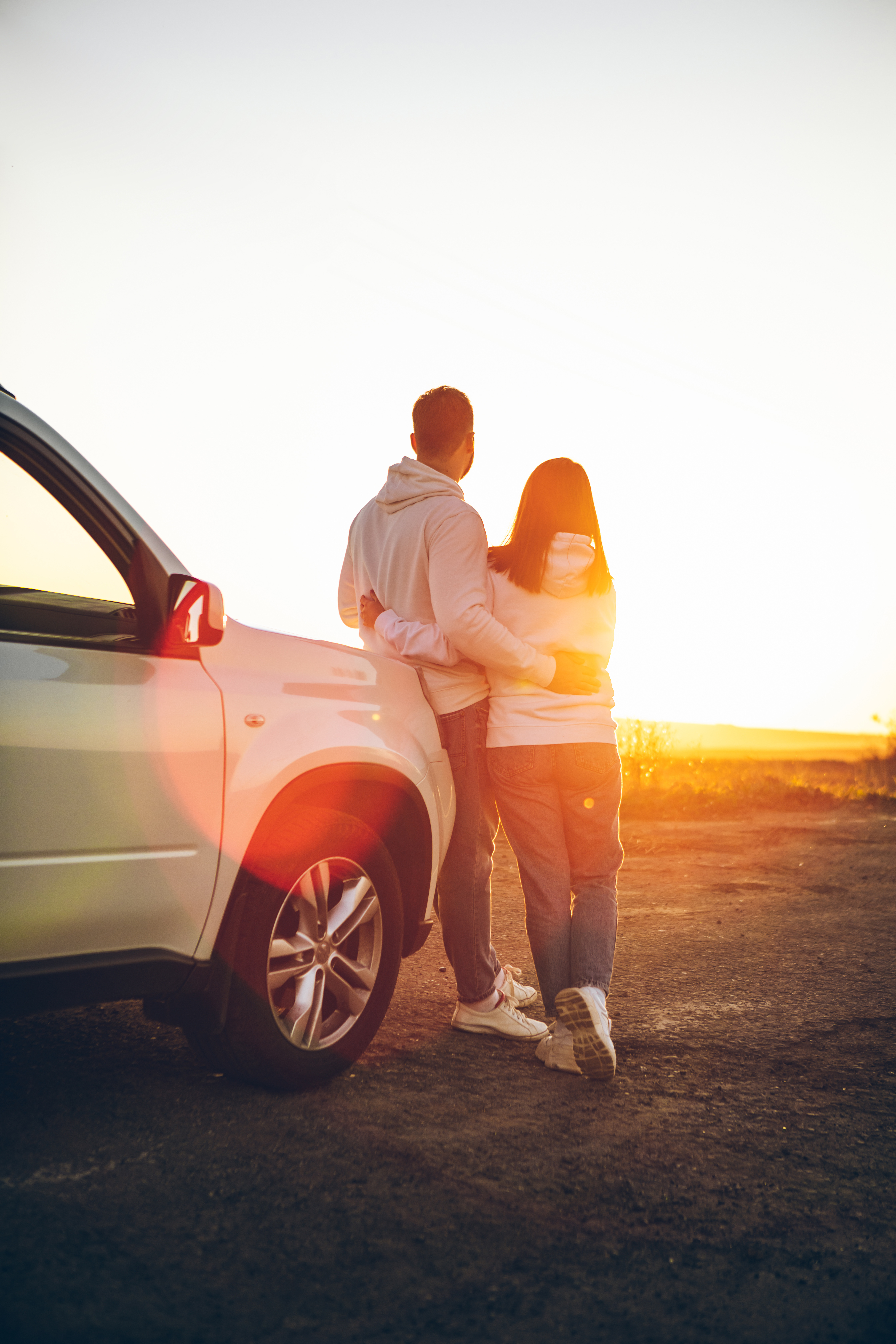 A couple standing by their car outdoors - learn how Light Lounge's back pain treatment can benefit you.