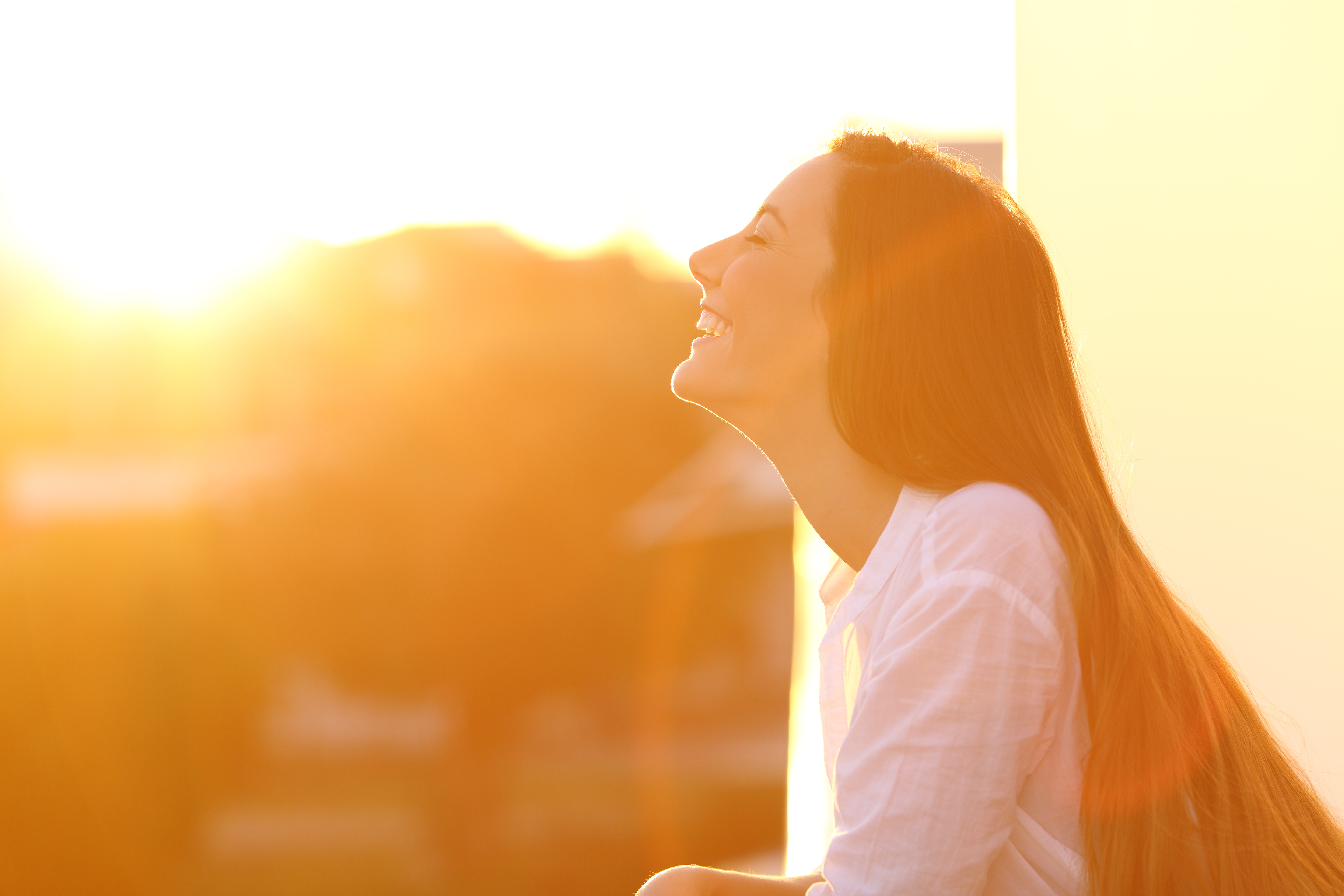 A pain-free woman in the sunlight - contact Light Lounge today to learn more about the benefits of our red light therapy pods.